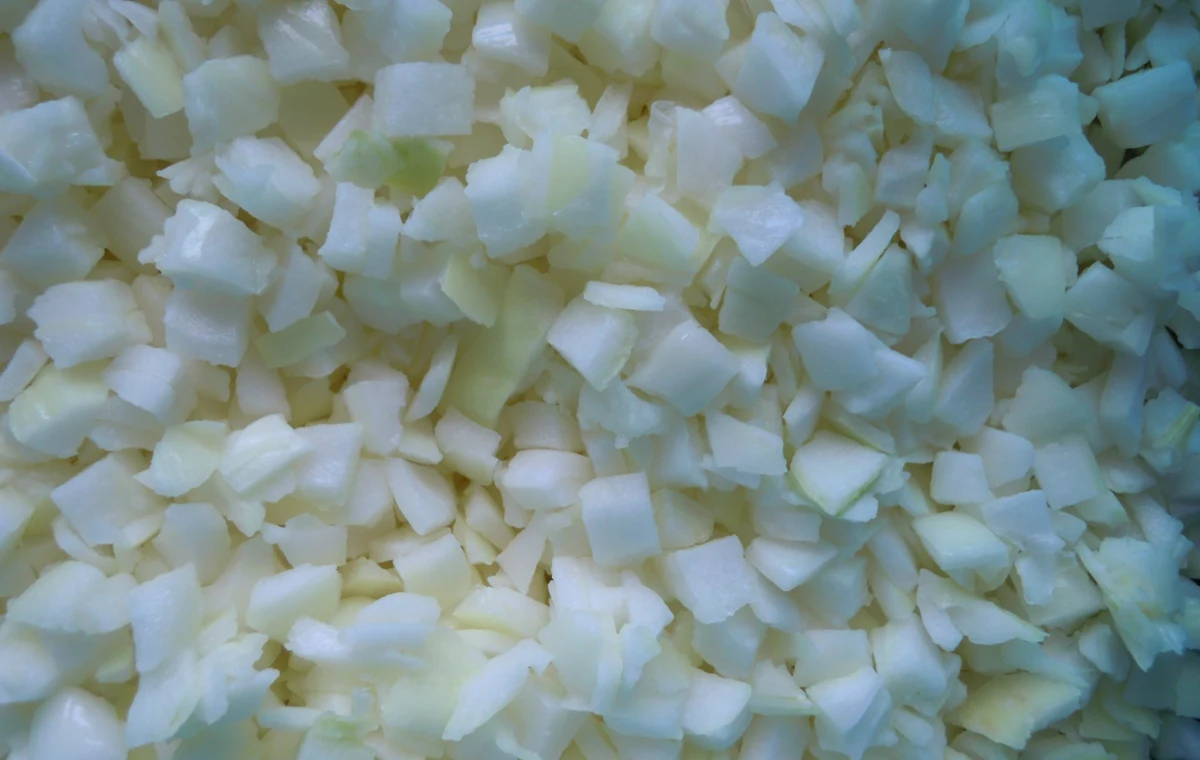 Real frozen onion dice and irregular pieces Close original photograph of frozen onion dice with layered irregular pieces and thin fragments