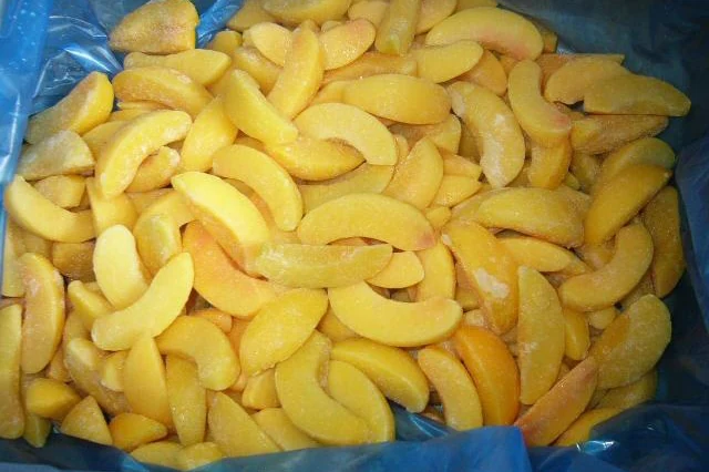 Rodajas de melocotón amarillo para revisar el color Rodajas de melocotón amarillo congelado en un recipiente con revestimiento azul, que muestran el corte antes de evaluar el color.