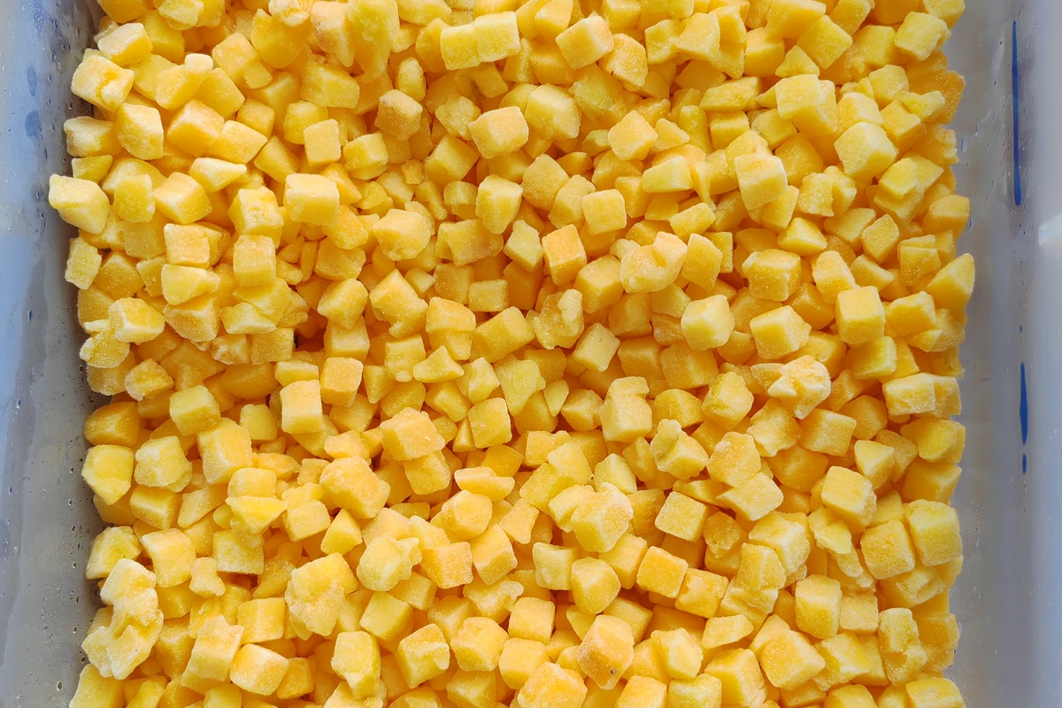 Dados de melocotón amarillo como segunda referencia de corte Dados de melocotón amarillo en una bandeja, que muestran un segundo corte con más superficies expuestas.