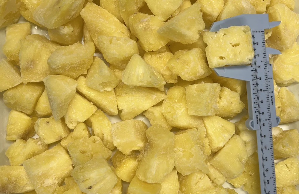 Frozen pineapple chunk form before grilling Large frozen pineapple chunks with a caliper for size context