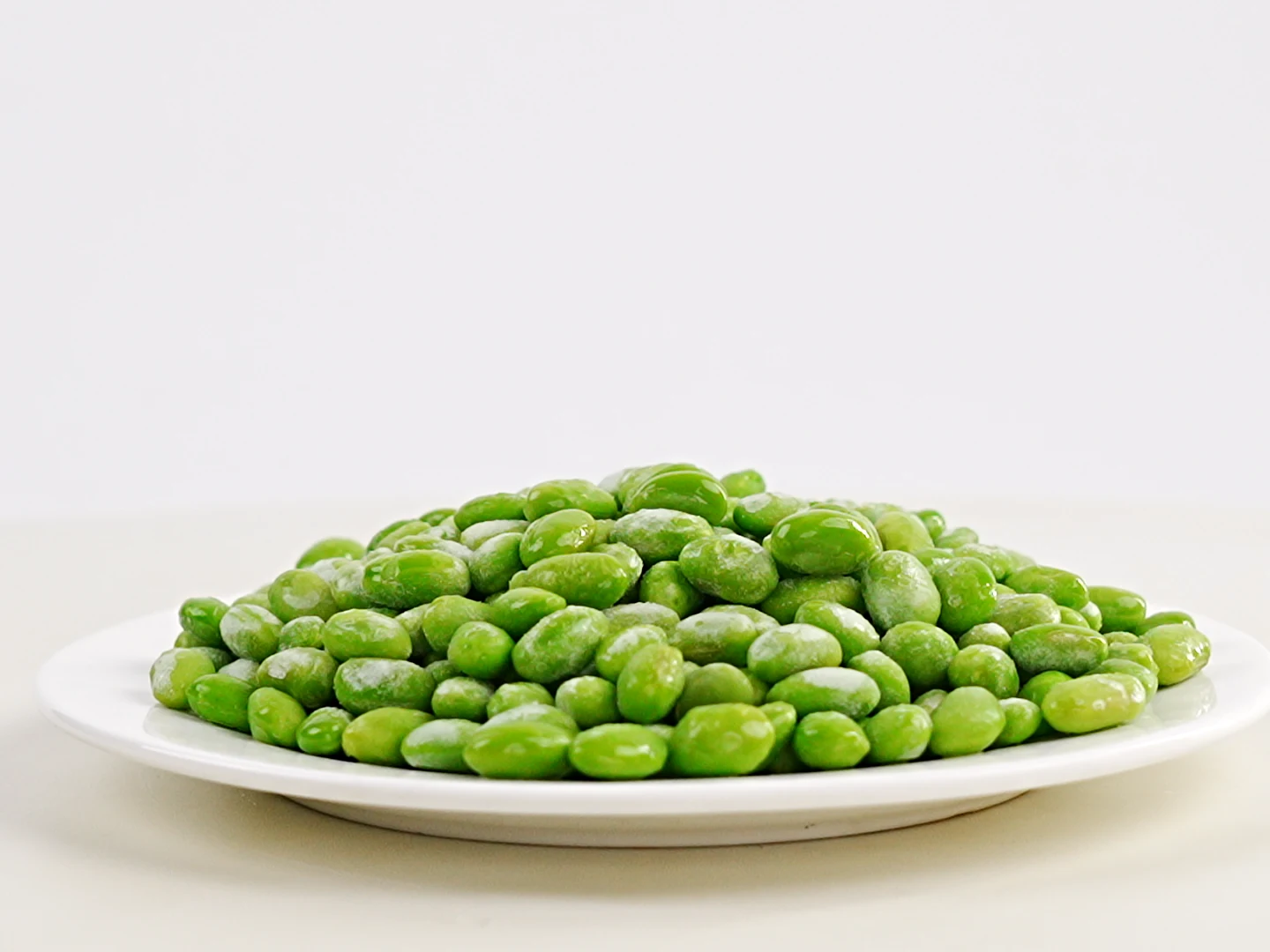 Examine kernel condition separately from the pod exterior Authentic original-video frame of shelled edamame beans on a white plate