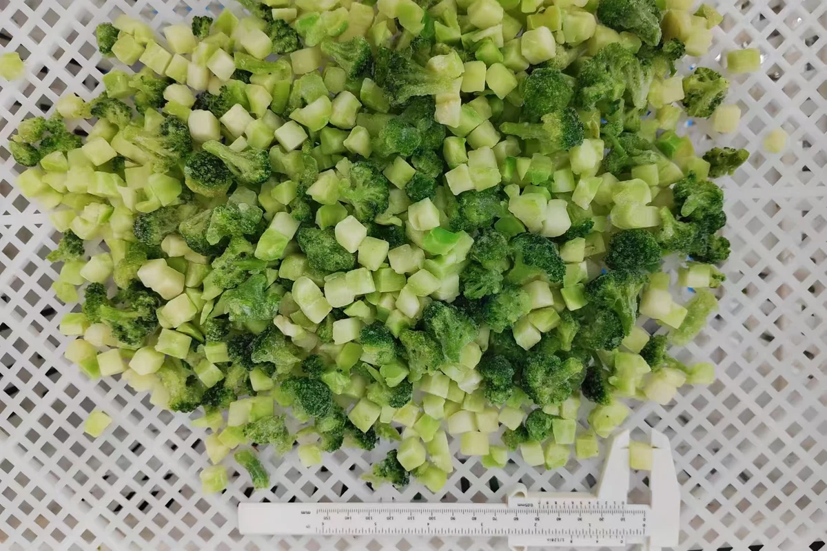 Ví dụ thật về bông cải cắt và thân cắt hạt lựu Miếng bông cải đông lạnh và thân cắt hạt lựu trên khay đục lỗ cùng thước đo cỡ, minh họa vì sao kiểu cắt chính xác cần có trong quy cách SKU