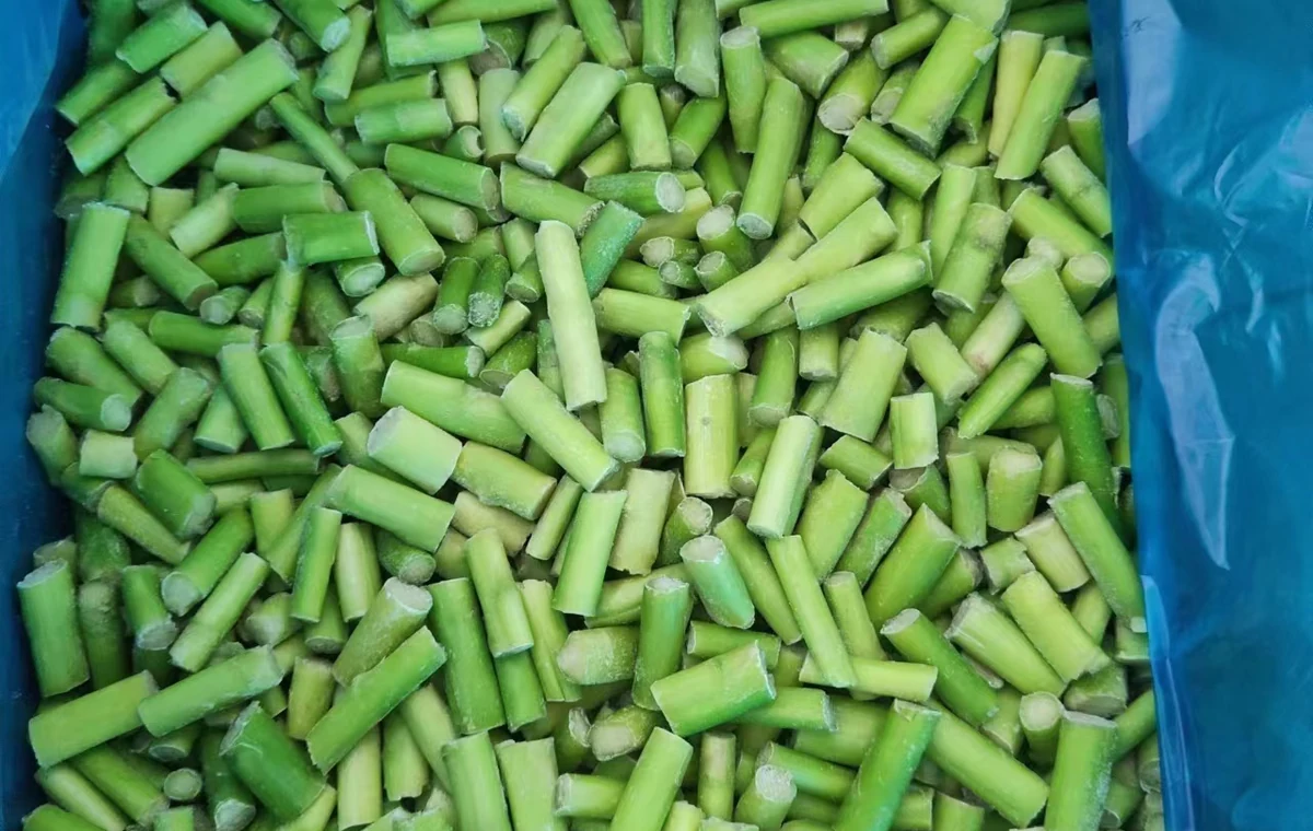 Unbranded original view of green frozen asparagus cut into short stem pieces inside a blue liner
