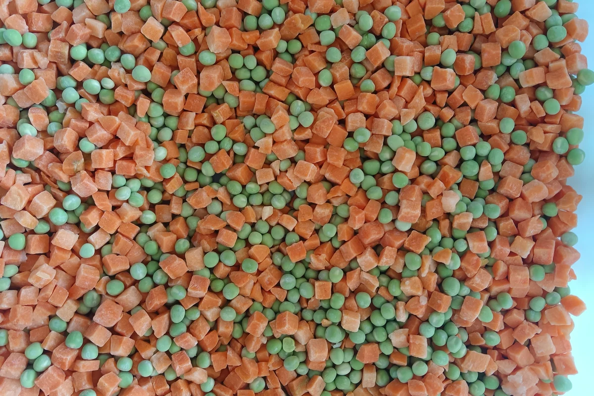 Peas within a mixed vegetable ingredient Top view of a frozen vegetable blend with green peas among carrot cubes