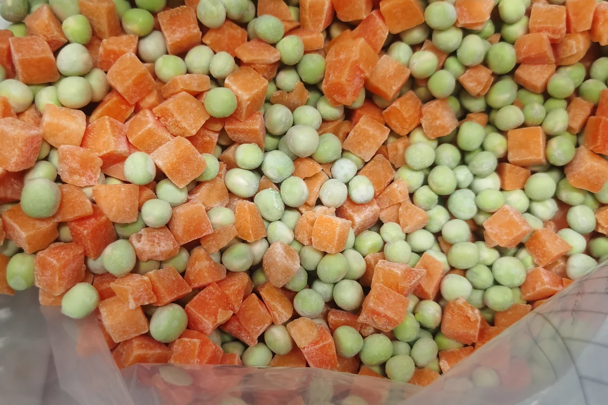 Recognize a pea and carrot blend Round green peas and orange carrot cubes together inside an unbranded liner