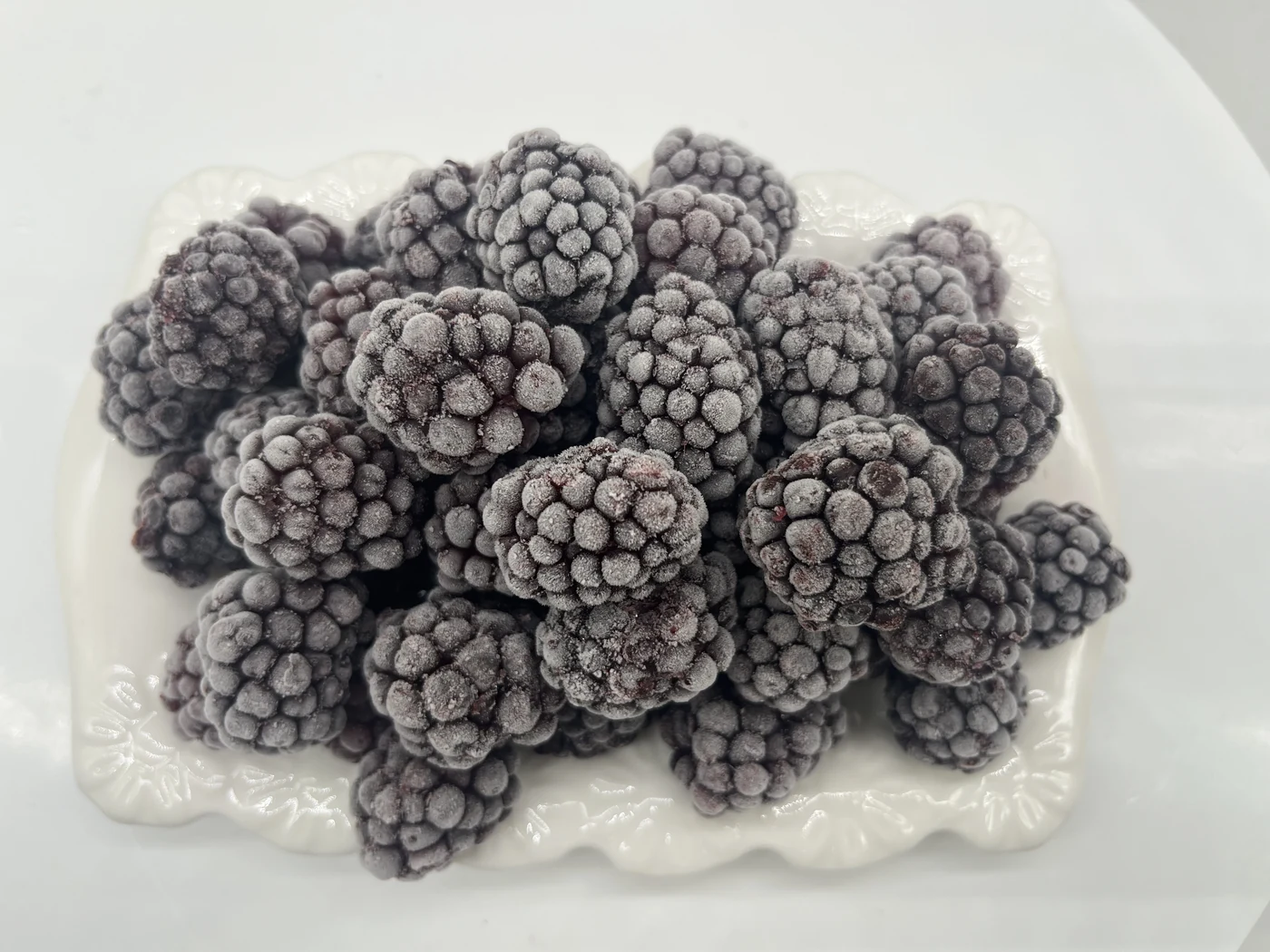 Moras enteras con escarcha visible Moras enteras con escarcha sobre plato blanco