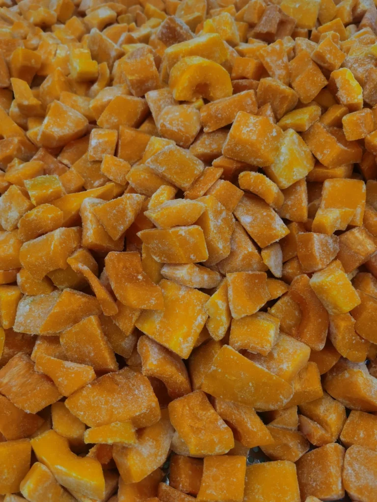 Orange gefrorene Kürbiswürfel mit sichtbarem Reif vor der Püreevorbereitung