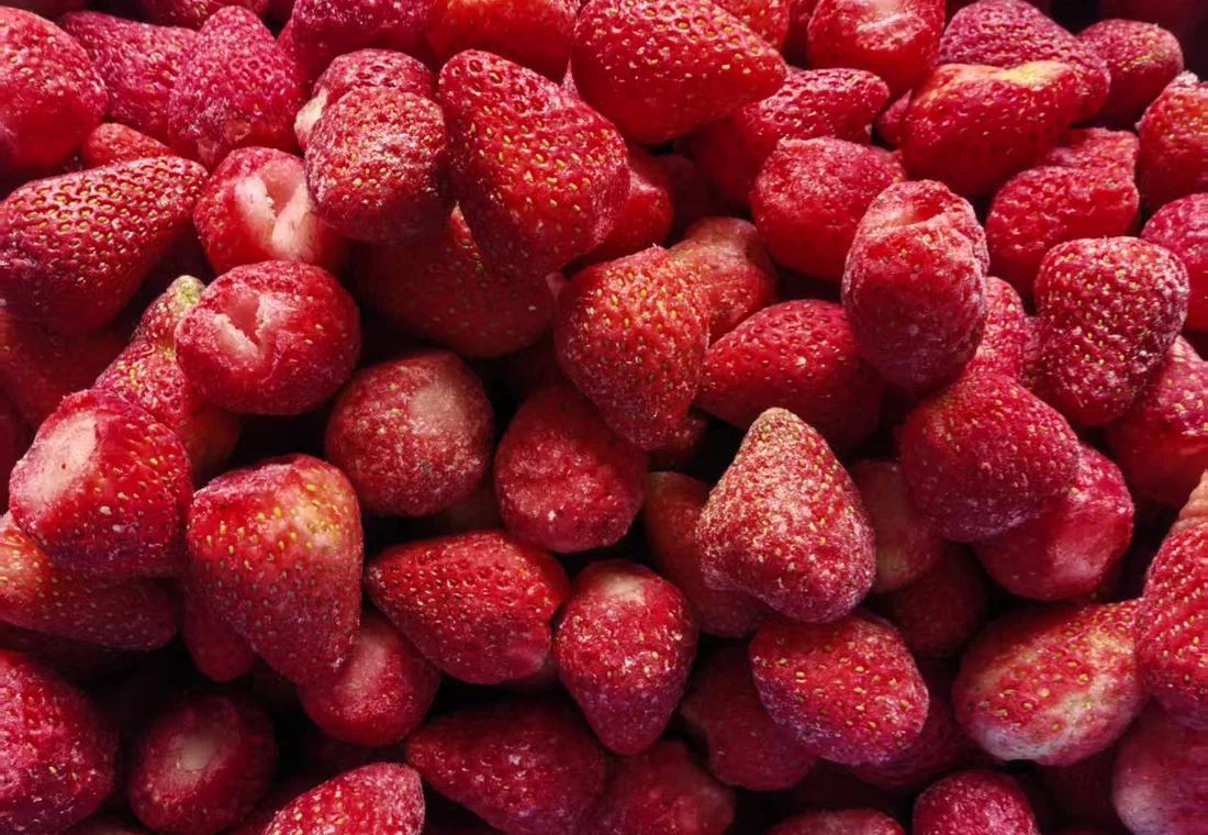 Close view of separate whole frozen strawberries with visible frost and hulled ends