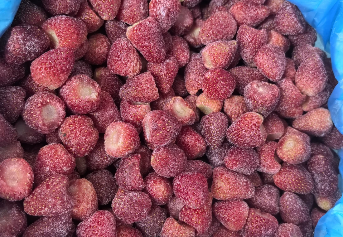 Whole hulled frozen strawberries in a blue-lined container, the starting fruit form for lemonade
