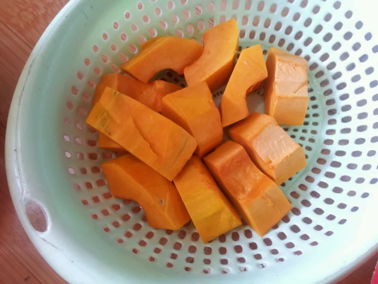 Orange pumpkin chunks in a pale green colander