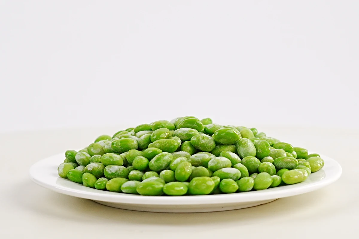 Shelled edamame for patties Shelled green edamame kernels on a plain white plate