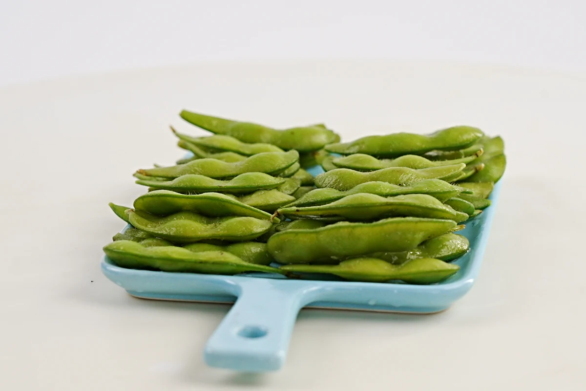 In-pod edamame contrast Whole green edamame pods on a blue tray