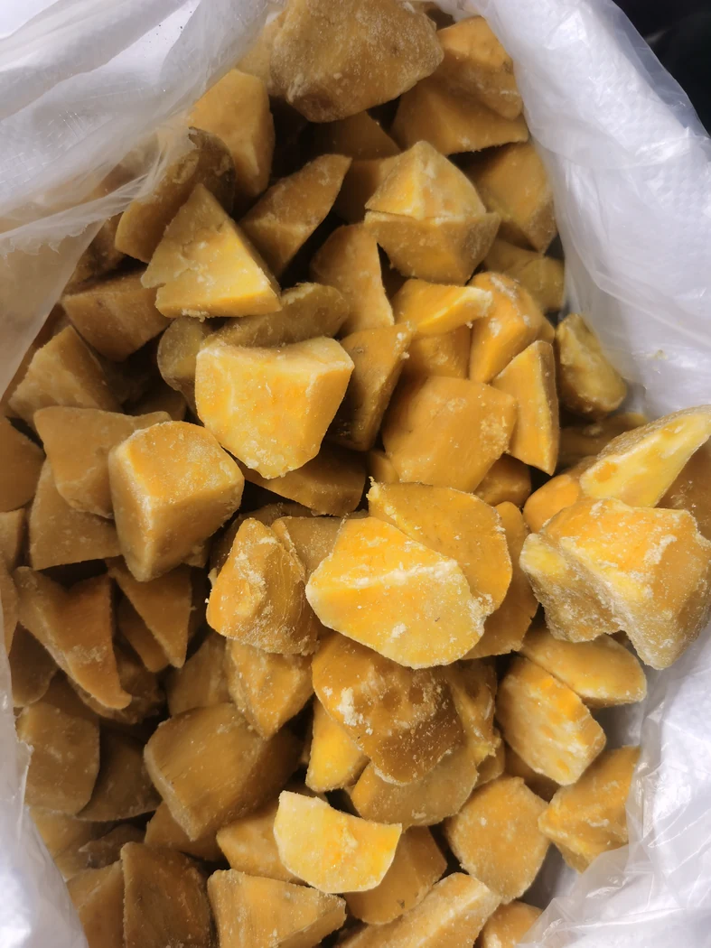 Irregular sweet potato chunks Irregular yellow orange sweet potato chunks in a white liner