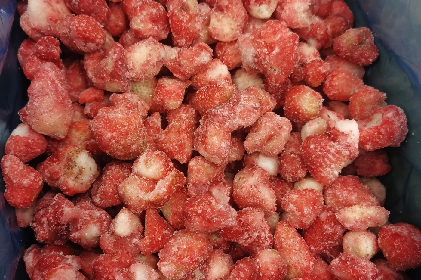 Frozen strawberry pieces in a plain blue liner
