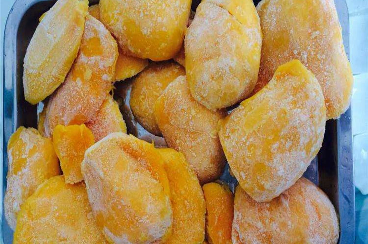 Frozen mango cheeks on an unbranded metal tray